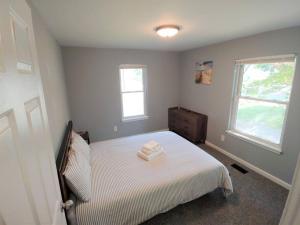 een slaapkamer met een bed en 2 ramen bij Relaxing Cottage by the Lake and Parking in Pontiac