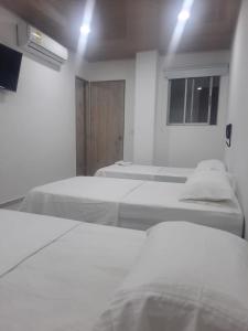 Habitación blanca con 2 camas y ventana en HOTEL MAR DEL CARIBE, en Soledad