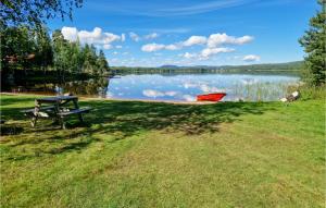 a picnic table in the grass next to a lake at Amazing Apartment In Vallsta With Wifi And 6 Bedrooms in Vallsta