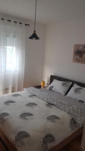 a bedroom with a bed with a black and white blanket at Apartman Chaplin in Vrnjačka Banja