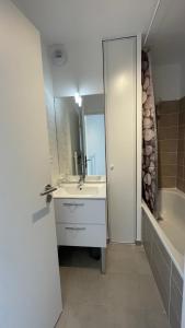 een badkamer met een wastafel, een bad en een spiegel bij Maison vue sur la Baie de Canche in Étaples