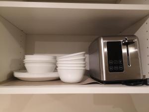 a kitchen shelf with bowls and a microwave at Jimmy B&B in Surrey