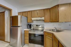 a kitchen with a stainless steel refrigerator and wooden cabinets at Sunrise Suites - Lakefront - Location Location in Wisconsin Dells