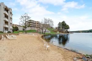 a beach with white chairs on the sand next to the water at Sunrise Suites - Lakefront - Location Location in Wisconsin Dells