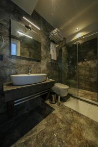 a bathroom with a sink and a shower and a toilet at AXU AIRPORT HOTEL in Arnavutköy