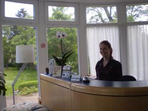 a woman sitting at a desk in a room with windows at Pension Celia in Wismar