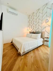 a bedroom with a large white bed and wooden floors at B&B Historia in Pozzuoli