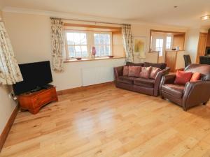 a living room with a couch and a flat screen tv at Long Cart Cottage in Embleton