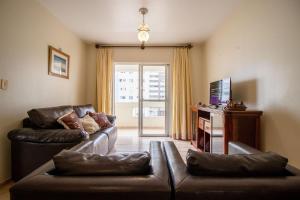 uma sala de estar com dois sofás de couro e uma televisão em CNI53 - 2 Dorm, Garagem, Climatizado, Wi-Fi em Balneário Camboriú