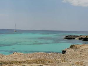 a blue pool of water with a boat in the ocean at Casa Sofia Favignana in Favignana