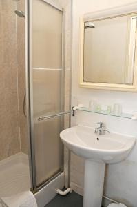 La salle de bains est pourvue d'un lavabo et d'une douche avec un miroir. dans l'établissement La Taverne des Deux Augustins, à Étretat