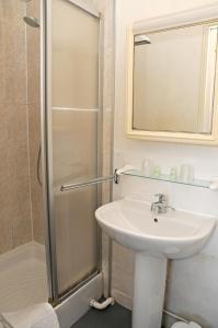 a bathroom with a sink and a shower with a mirror at La Taverne des Deux Augustins in Étretat