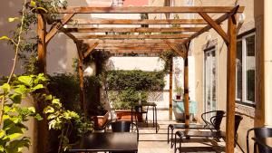 a wooden pergola with chairs and tables on a patio at Casa do Jasmim by Shiadu in Lisbon