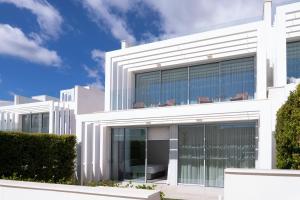 ein weißes Gebäude mit großen Glasfenstern in der Unterkunft Villa La Perla Sotogrande - since 2022 - Sea View - 3 Bedrooms and Bathrooms - La Reserva Beach and Golf nearby in Sotogrande