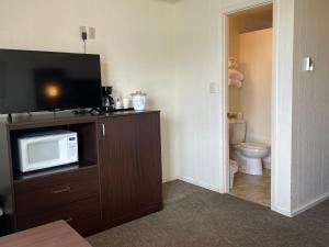 a room with a bathroom with a tv and a toilet at Holiday Motel in Westport