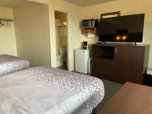 a hotel room with a bed and a flat screen tv at Holiday Motel in Westport