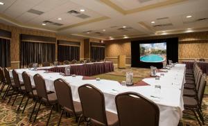 a conference room with long tables and chairs and a screen at Holiday Inn Resort Orlando - Lake Buena Vista by IHG in Orlando +100 photos