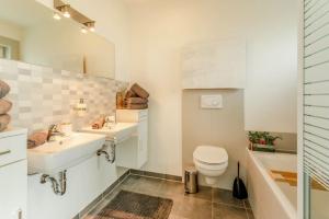 a bathroom with two sinks and a toilet and a tub at Dolomites Bungalow Eifelsteig w view Terrace BBQ in Gerolstein +10 photos