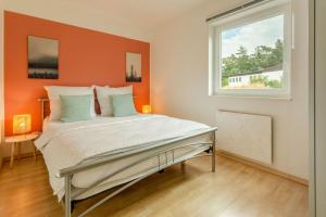 1 dormitorio con 1 cama con pared de color naranja en Dolomites Bungalow Eifelsteig w view Terrace BBQ, en Gerolstein