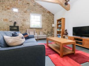 a living room with a blue couch and a tv at Wheal Grey in Germoe