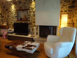 een woonkamer met een witte stoel en een tv bij Villa Ria 