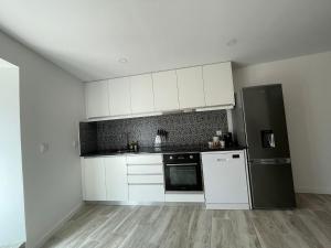 a kitchen with white cabinets and a black refrigerator at Casinha da fonte in Arcos de Valdevez