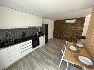 a kitchen with white cabinets and a wooden table with a dining room at Casinha da fonte in Arcos de Valdevez