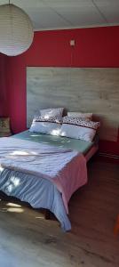 een slaapkamer met een groot bed met een rode muur bij L'Etape gourmande, chambres d'hôtes in Wellin