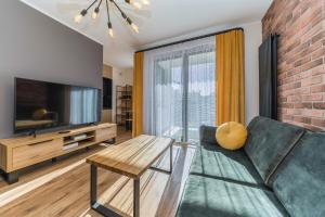 a living room with a couch and a television at Lumen Billberry Apartments in Gdańsk