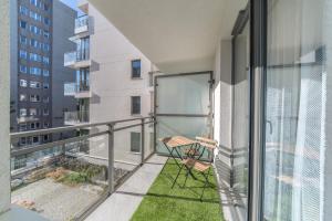a balcony with a table and chair on a building at Lumen Billberry Apartments in Gdańsk