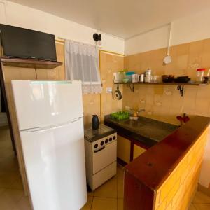uma cozinha com um frigorífico branco e um fogão em Chales Virena em Ubatuba