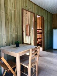 プライア・ド・ローザにあるCabanas Premaの冷蔵庫付きの客室で、木製のテーブルと椅子が備わります。