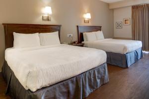 a hotel room with two beds with white sheets at Howard Johnson by Wyndham Amherst Hadley in Amherst