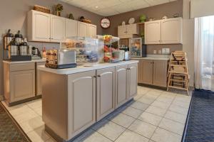 a large kitchen with white cabinets and a counter at Howard Johnson by Wyndham Amherst Hadley in Amherst