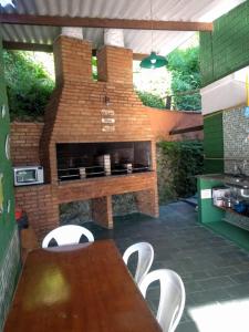 un patio con chimenea de ladrillo, mesa y sillas en Chales Virena, en Ubatuba