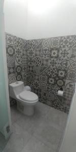 a bathroom with a toilet and a tiled wall at Hotel Lucero Chan in Santa María del Oro