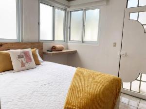 a bedroom with a bed with a yellow blanket and windows at Detailed and Modern Apartment D in Guatemala