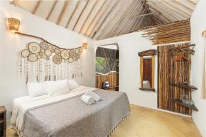 a bedroom with a bed and a window at Yaxchen Tulum Cabañas & Cenote in Tulum