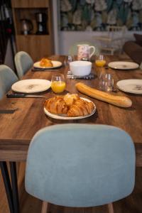 a wooden table with a plate of croissants and orange juice at *OKALEE* in Dinan