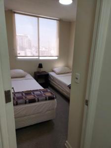 dwa łóżka w pokoju z oknem w obiekcie DEPARTAMENTOS SANTIAGO CENTRO #3 w mieście Santiago