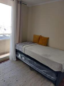 a bed sitting in a bedroom next to a window at DEPARTAMENTOS SANTIAGO CENTRO #3 in Santiago