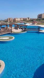a pool of blue water with benches and a bridge at El Ain El Sokhna-Villa at Piacera Resort Seaview in Ain Sokhna