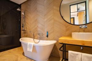 y baño con bañera, lavabo y espejo. en Santa Natura Resort & SPA, 