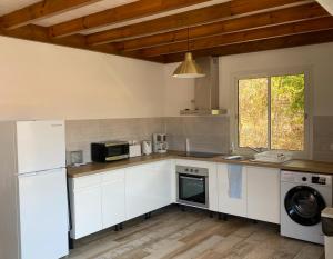 cocina con armarios blancos, lavadora y secadora en Haut de villa Taalia, en Terre-de-Haut