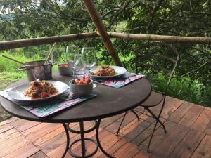 una mesa con dos platos de comida en una cubierta en Glamping El Árbol en la Casa en San Antonio del Tequendama