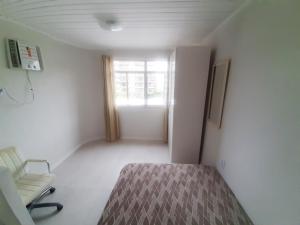 ein Schlafzimmer mit einem Bett, einem Stuhl und einem Fenster in der Unterkunft Leblon Central in Rio de Janeiro