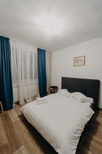 ein großes weißes Bett in einem Zimmer mit blauen Vorhängen in der Unterkunft Apartamentul Albastru in Vatra Dornei