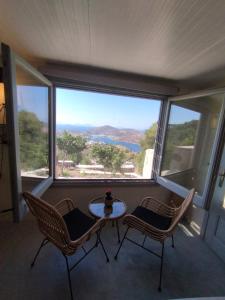 a balcony with a table and chairs in front of a window at TRADITIONAL STUDIO Chora Patmos in Patmos