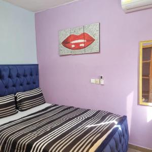 a bedroom with a bed with a red lips picture on the wall at Residence Sighaka - Gold Apartment - WiFi, Gardien, Parking in Douala