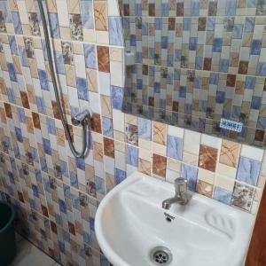 a bathroom with a sink and tiles on the wall at Residence Sighaka - Premium VIP Apartment - WiFi, Gardien, Parking in Douala